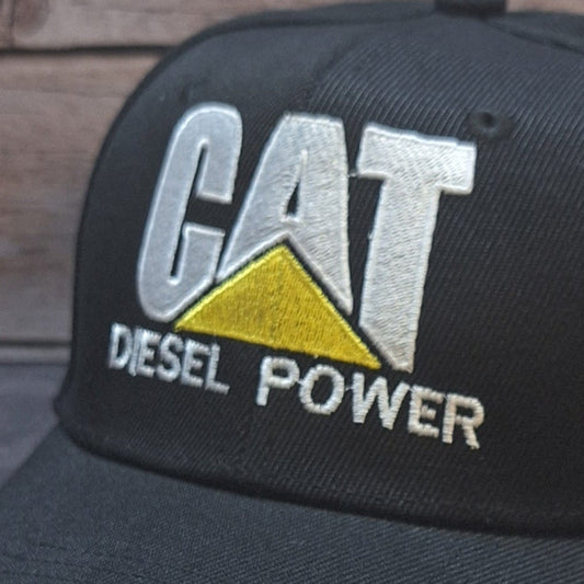 Black cap with 'CAT Diesel Power' logo on a wooden surface