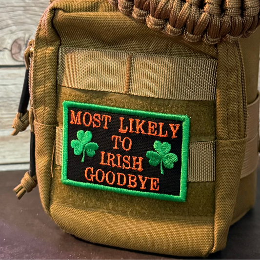 A close-up of a tan tactical pouch featuring a rectangular embroidered patch that reads 'MOST LIKELY TO IRISH GOODBYE' in orange lettering with green shamrocks and a green border.