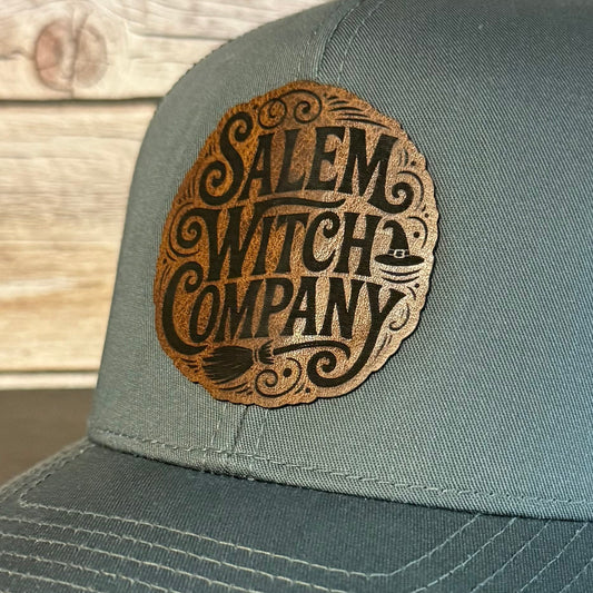 Gray cap with 'Salem Witch Company' logo on a wooden surface