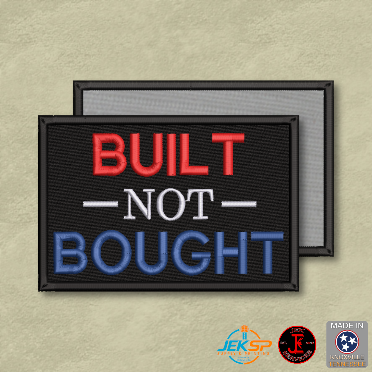 Built Not Bought embroidered morale patch with red, white, and blue lettering on black fabric, genuine hook backing, and gray loop panel displayed behind.