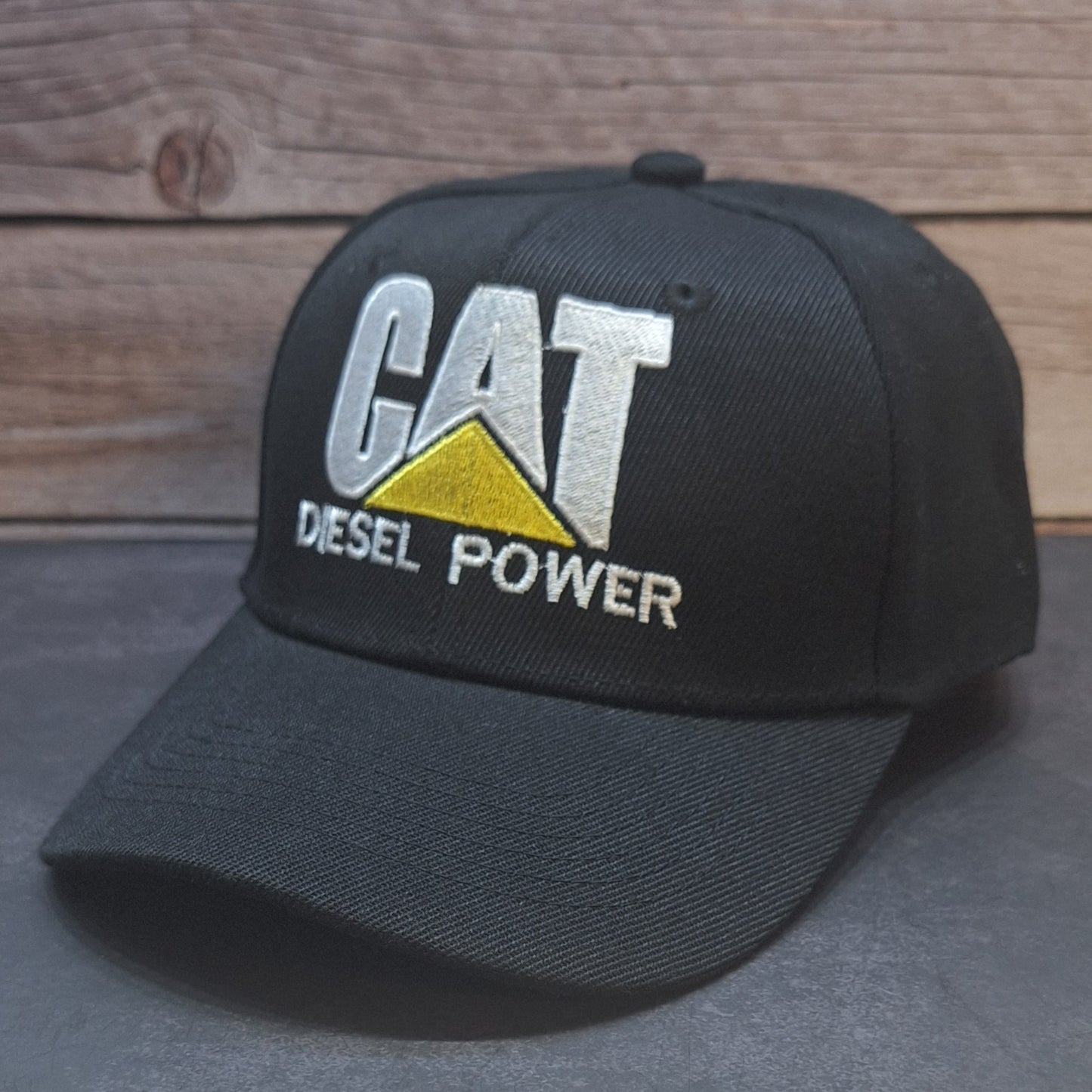 Black cap with 'CAT Diesel Power' logo on a wooden surface