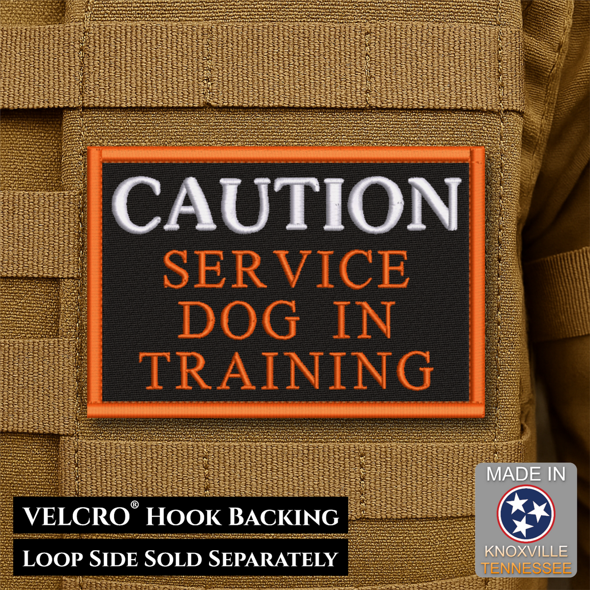 A rectangular embroidered patch with a black background and orange border, reading “CAUTION SERVICE DOG IN TRAINING,” shown attached to tan tactical gear. Text at the bottom says VELCRO™ Hook Backing and LOOP SIDE SOLD SEPARATELY, and a “Made in Knoxville Tennessee” badge appears in the lower right.