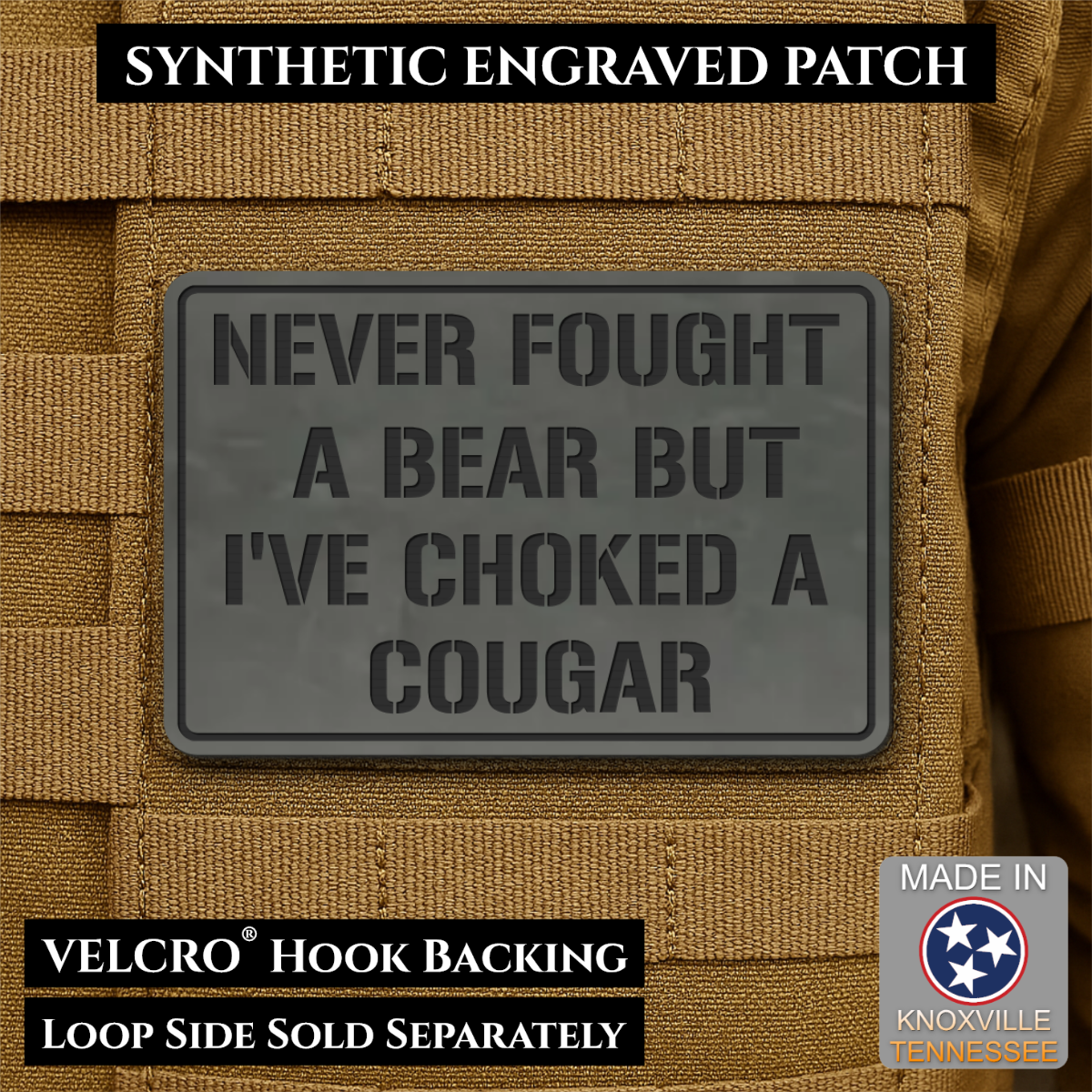 I’ve Choked A Cougar laser-engraved synthetic morale patch: a dark gray rectangular synthetic engraved patch with embossed text reading 'NEVER FOUGHT A BEAR BUT I'VE CHOKED A COUGAR,' shown attached to tan tactical vest fabric.