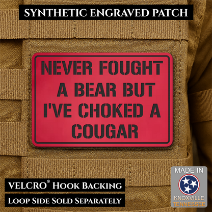 I’ve Choked A Cougar laser-engraved synthetic morale patch: a rectangular red synthetic engraved patch with black text reading “NEVER FOUGHT A BEAR BUT I’VE CHOKED A COUGAR,” shown attached to tan tactical vest fabric. Text.