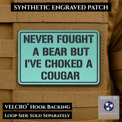 I’ve Choked A Cougar laser-engraved synthetic morale patch: a rectangular synthetic engraved patch with a mint green background and black text reading 'NEVER FOUGHT A BEAR BUT I'VE CHOKED A COUGAR,' shown attached to tan tactical.