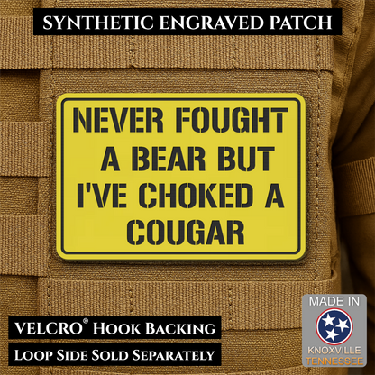 I’ve Choked A Cougar laser-engraved synthetic morale patch: a yellow rectangular synthetic engraved patch with black text reading 'NEVER FOUGHT A BEAR BUT I'VE CHOKED A COUGAR' shown attached to tan tactical vest fabric. Black text.
