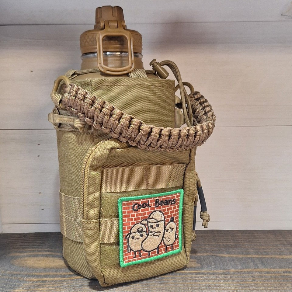 A tan tactical water bottle pouch with a matching paracord carrying strap, holding a brown water bottle. The pouch features a front zippered pocket with a green-bordered patch that reads 'Cool Bears'.
