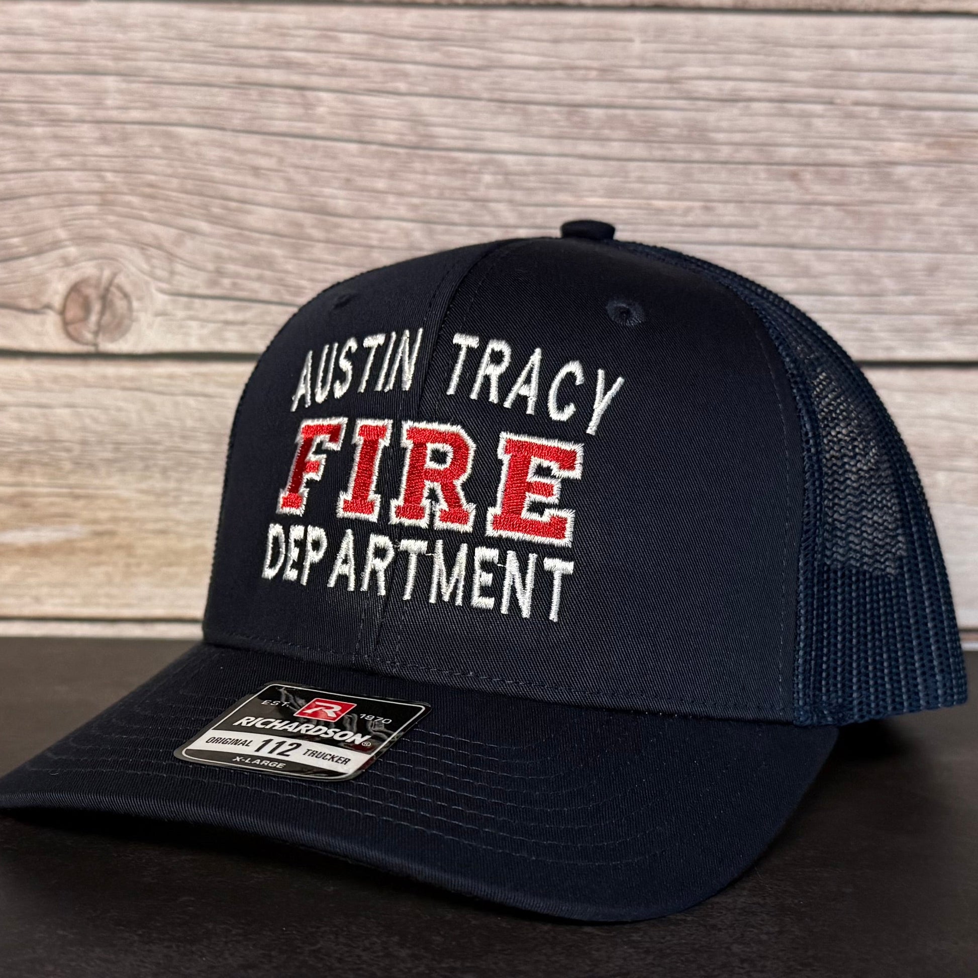 Black cap with 'Austin Tracy Fire Department' text on a wooden background