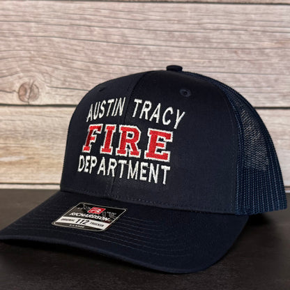 Black cap with 'Austin Tracy Fire Department' text on a wooden background