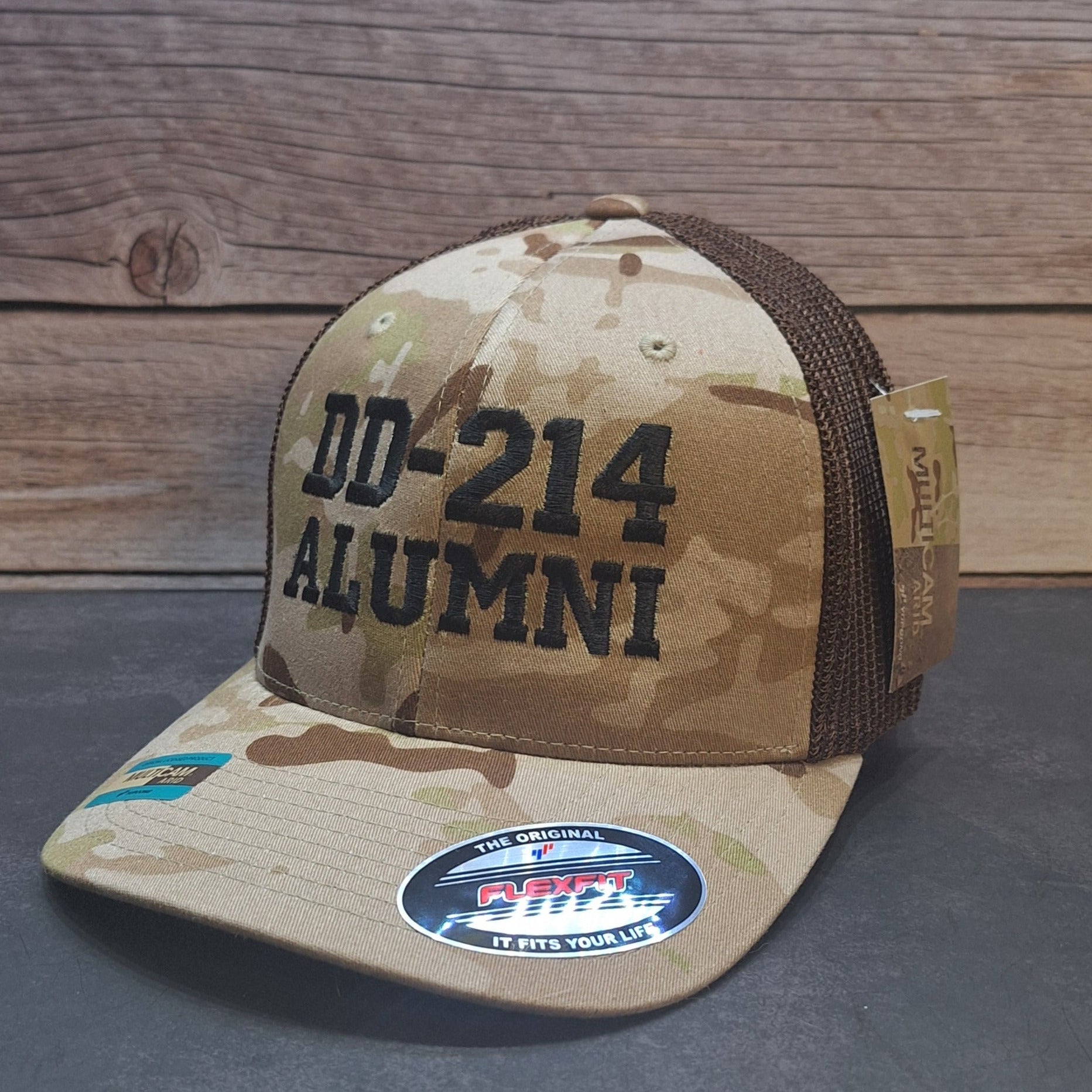 Camouflage cap with 'DD-214 ALUMNI' text on a wooden background