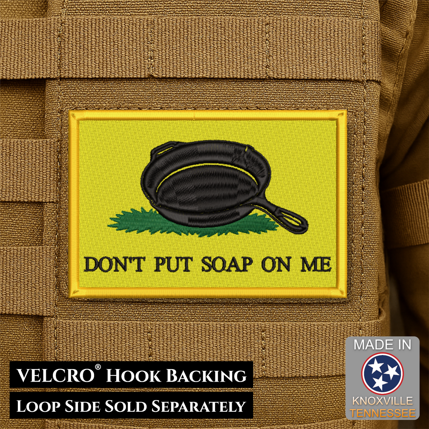 A rectangular embroidered patch with a yellow background, a black cast-iron skillet, green grass, and the text 'DON'T PUT SOAP ON ME' attached to tan tactical webbing. Text at the bottom reads 'VELCRO HOOK BACKING' and 'LOOP SIDE SOLD SEPARATELY'; a 'Made in Knoxville Tennessee' badge appears in the lower right.