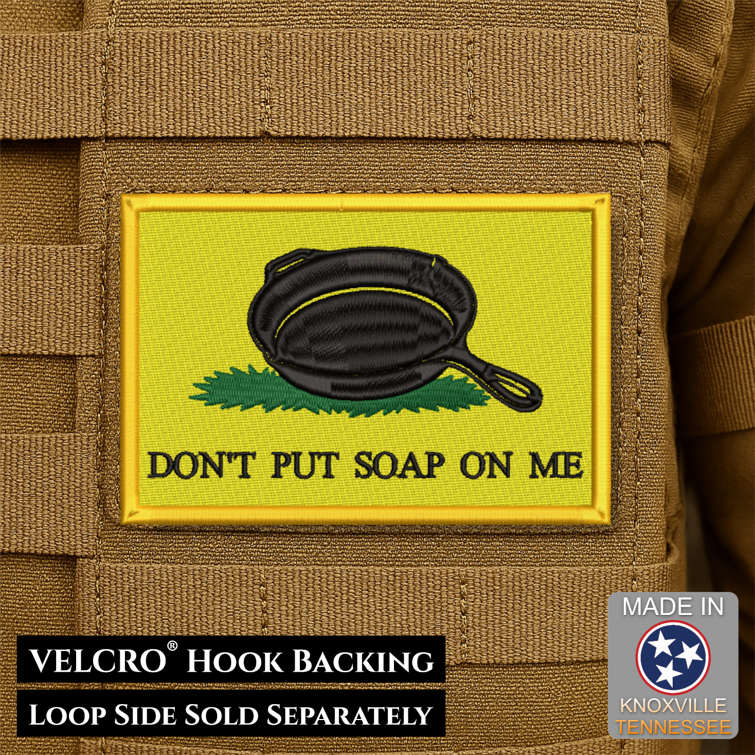 A rectangular embroidered patch with a yellow background, a black cast-iron skillet, green grass, and the text 'DON'T PUT SOAP ON ME' attached to tan tactical webbing. Text at the bottom reads 'VELCRO HOOK BACKING' and 'LOOP SIDE SOLD SEPARATELY'; a 'Made in Knoxville Tennessee' badge appears in the lower right.