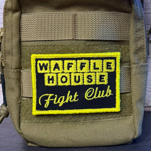 An olive green tactical pouch featuring a rectangular embroidered patch with a black background, yellow border, and yellow text reading 'WAFFLE HOUSE Fight Club'.