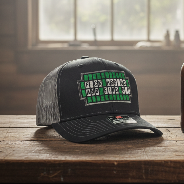 Black cap with green text on a wooden table next to a brown bottle.