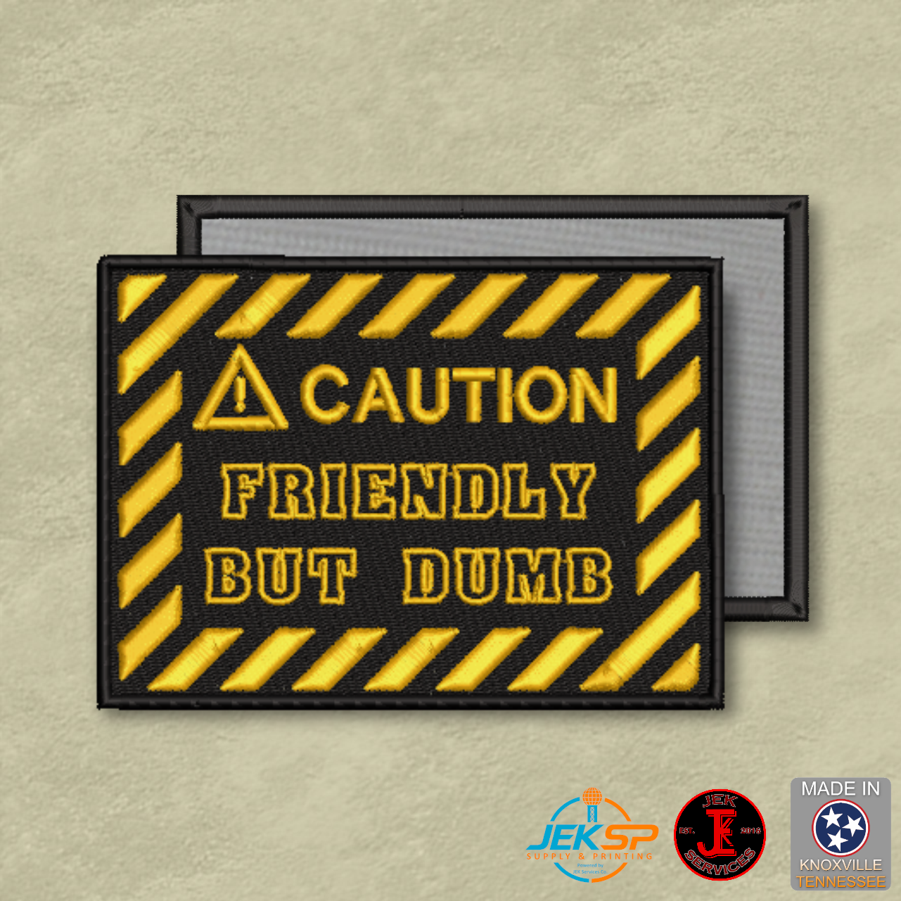 Black and yellow caution-style embroidered morale patch reading "Friendly But Dumb" with genuine VELCRO® hook backing, made in Tennessee for tactical gear.