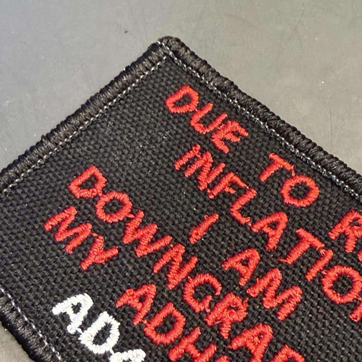 A close-up of a black embroidered patch with red and white text reading 'DUE TO R.