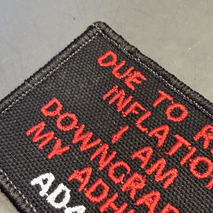 A close-up of a black embroidered patch with red and white text reading 'DUE TO R.