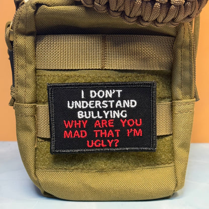 A close-up of a tactical pouch in olive drab green nylon with a black embroidered patch on the front. The patch features white and red text that reads, 'I DON'T UNDERSTAND BULLYING WHY ARE YOU MAD THAT I'M UGLY?'.