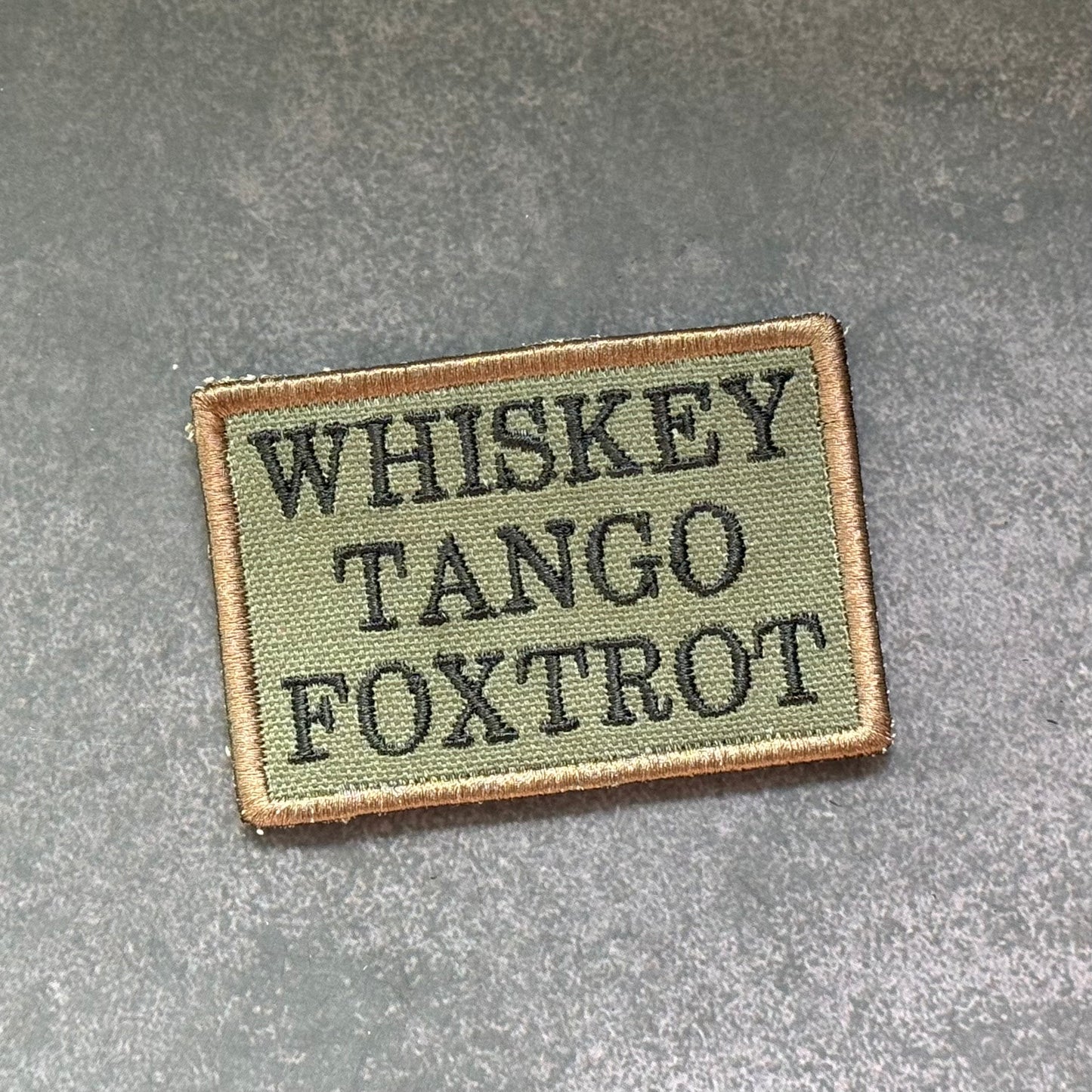 Olive drab Whiskey Tango Foxtrot embroidered morale patch with black lettering and VELCRO hook backing