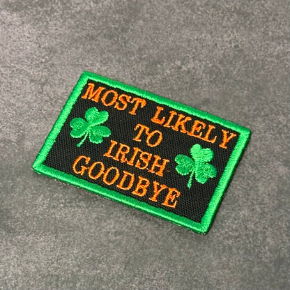 Black embroidered morale patch with green border, green shamrocks, and orange text reading "Most Likely To Irish Goodbye" displayed on a gray background.
