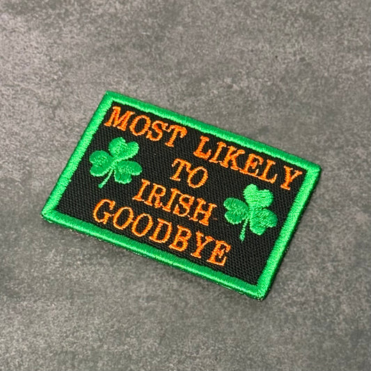 Black embroidered morale patch with green border, green shamrocks, and orange text reading "Most Likely To Irish Goodbye" displayed on a gray background.