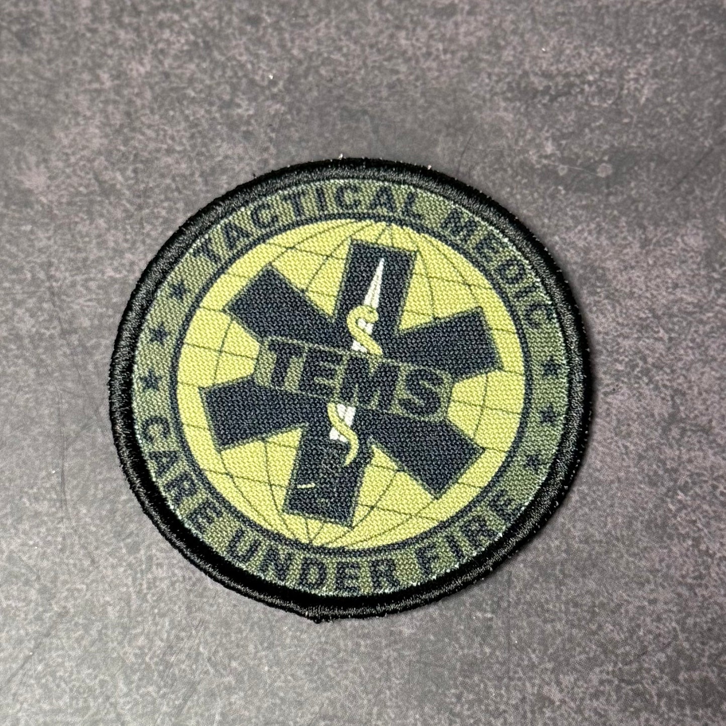 Circular patch with tactical and medical symbols on a gray background