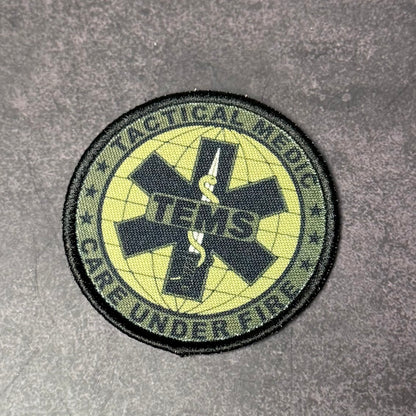 Circular patch with tactical and medical symbols on a gray background