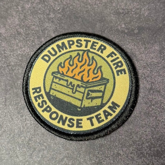 Round embroidered morale patch featuring a flaming dumpster graphic and the words "Dumpster Fire Response Team" on a tan and black background displayed on a gray textured surface.