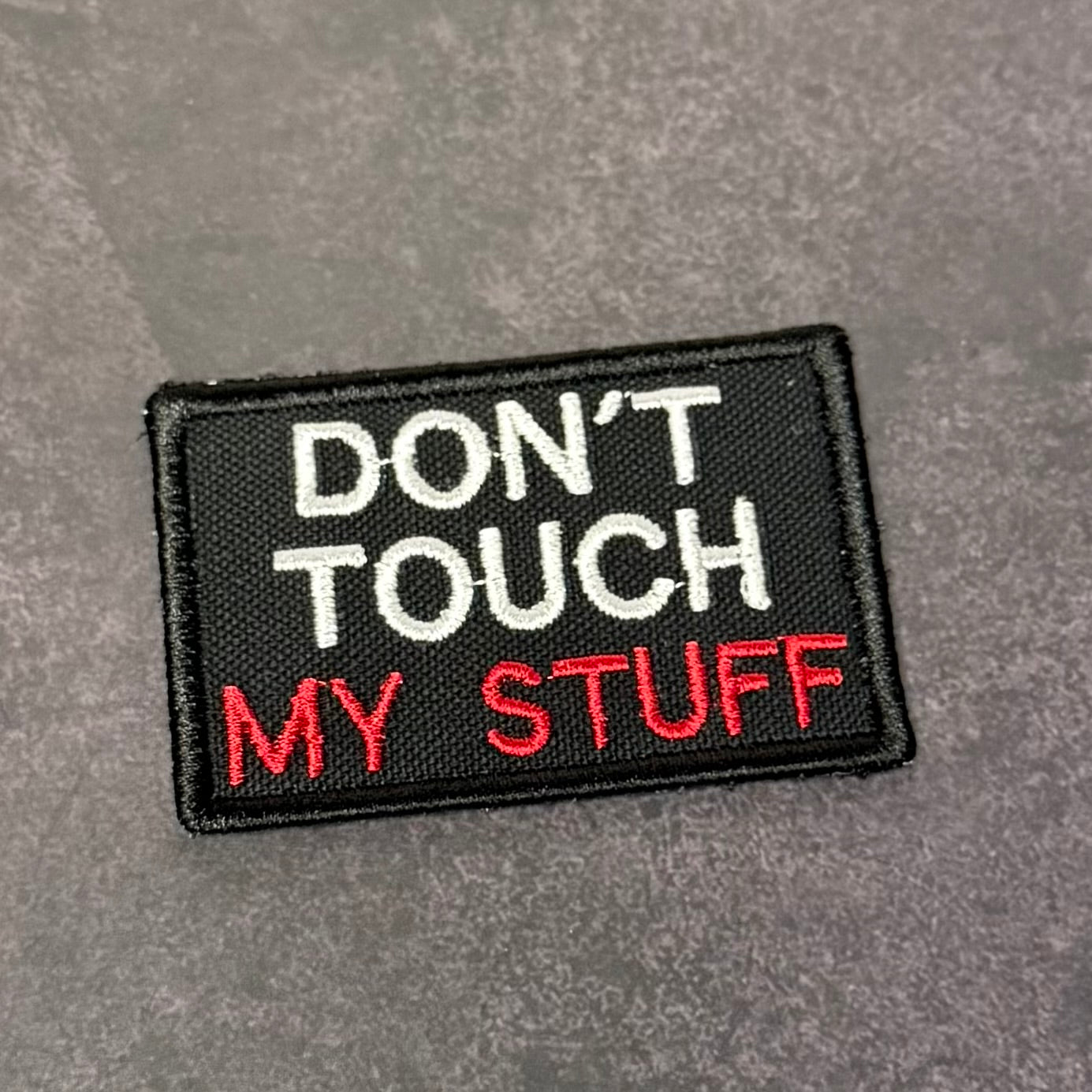Black embroidered morale patch with white and red text reading "Don't Touch My Stuff" displayed on a gray background.