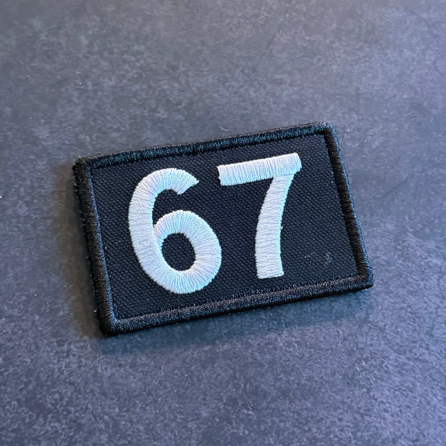 Black embroidered 67 morale patch with gray numbers and hook backing