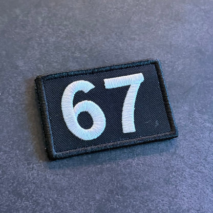 Black embroidered 67 morale patch with gray numbers and hook backing