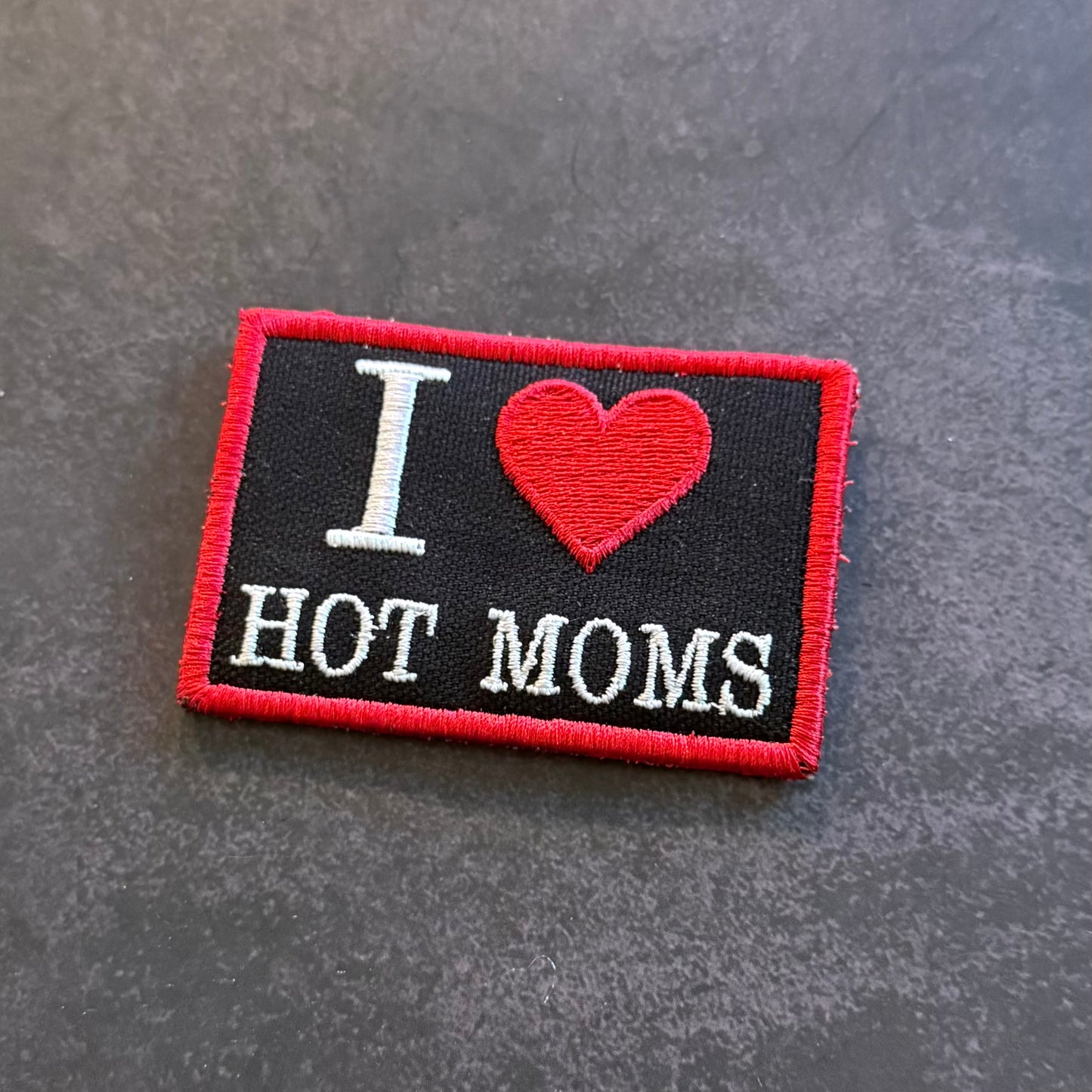 Black embroidered I Love Hot Moms morale patch with red heart design and red border