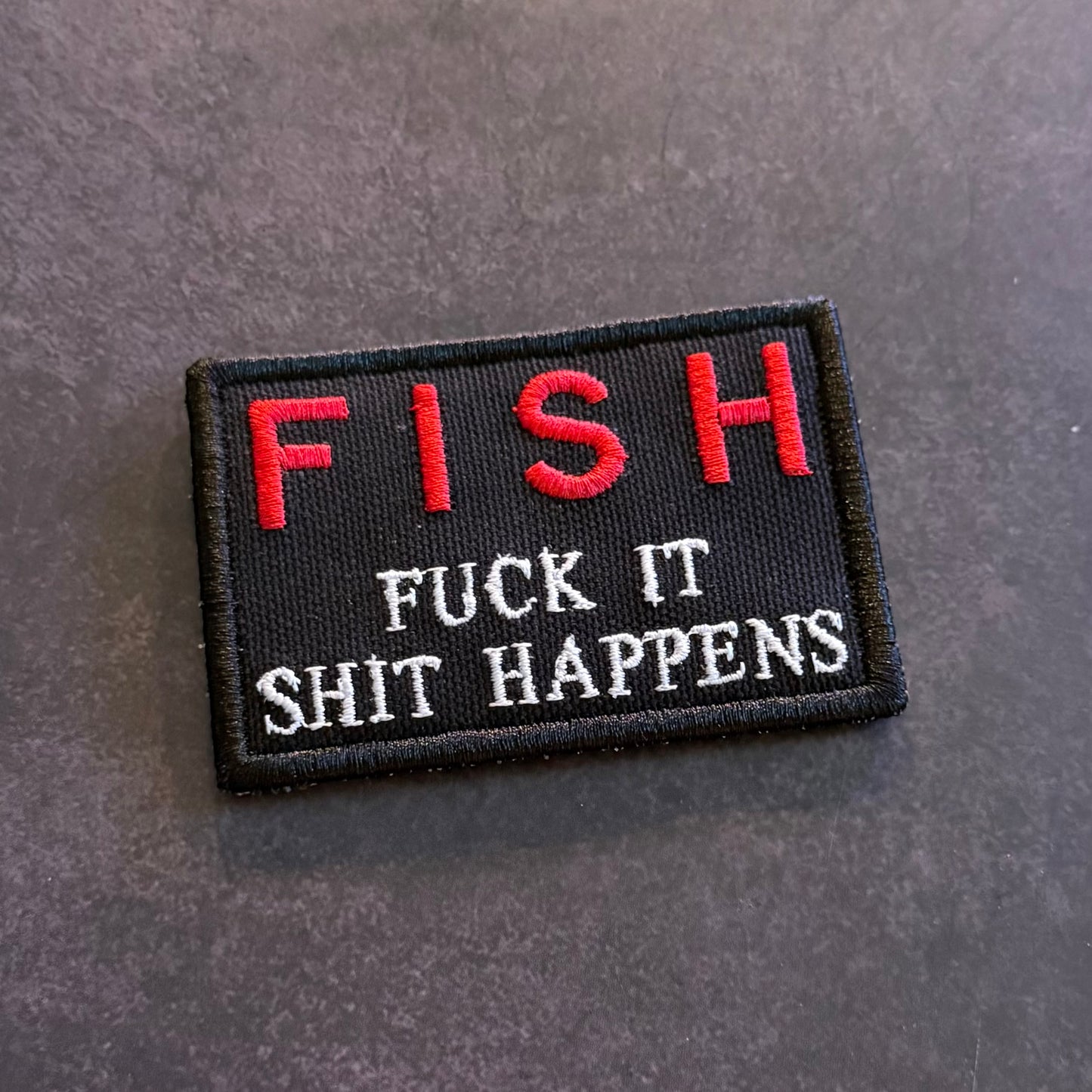 Black embroidered FISH Fuck It Shit Happens morale patch with red and white lettering and VELCRO hook backing