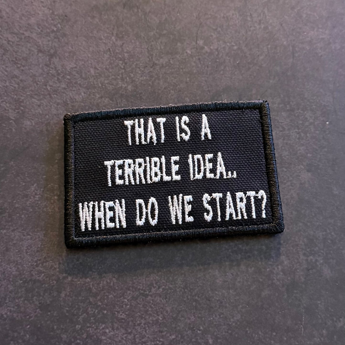 Black embroidered That's a Terrible Idea When Do We Start morale patch with white lettering and VELCRO hook backing