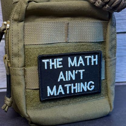 An olive green tactical pouch with a black embroidered patch that reads 'THE MATH AIN'T MATHING' in white text, shown against a rustic wood background.