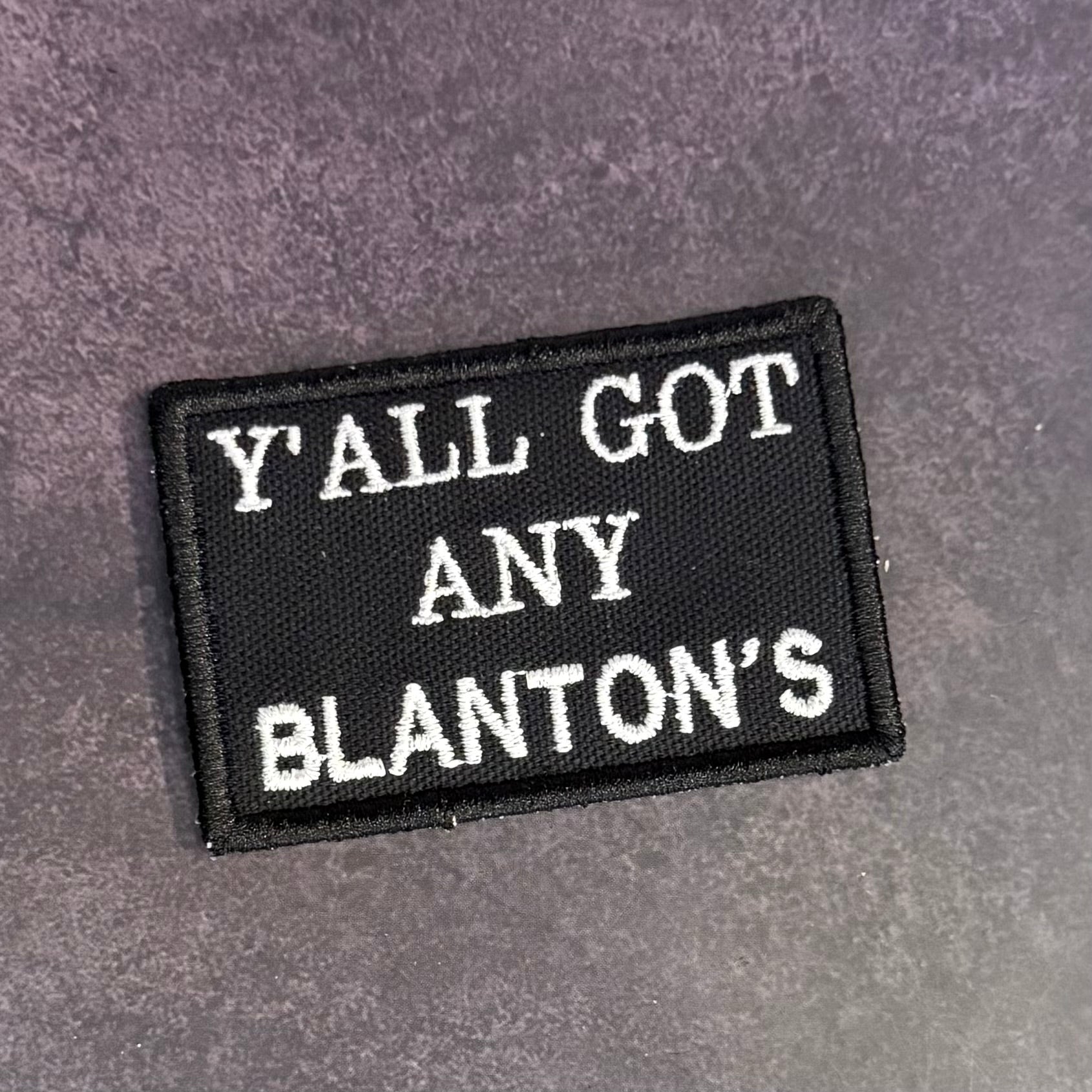 A rectangular black embroidered patch with white text reading 'Y'ALL GOT ANY BLANTON'S' on a textured gray background.