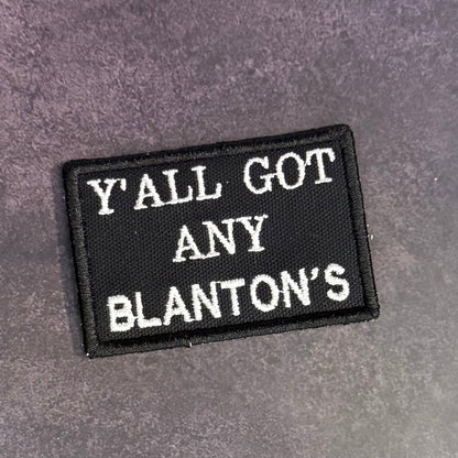 A rectangular black embroidered patch with white text reading 'Y'ALL GOT ANY BLANTON'S' on a textured gray background.