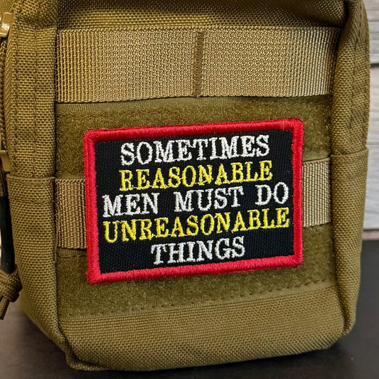 An olive green tactical pouch with a black embroidered patch featuring the text 'SOMETIMES REASONABLE MEN MUST DO UNREASONABLE THINGS' in white and yellow, with a red border.