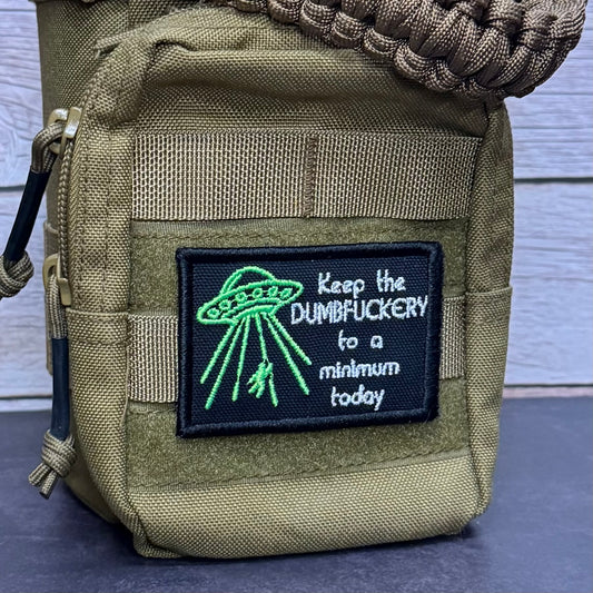 An olive drab tactical pouch with a black embroidered patch featuring a green UFO and the text 'Keep the DUMBFUCKERY to a minimum today'.