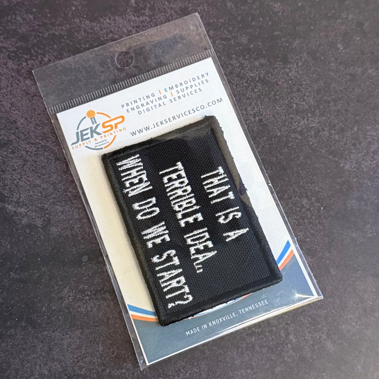 A black rectangular embroidered patch with white text reading 'WHEN DO WE START? THAT'S A TERRIBLE IDEA.