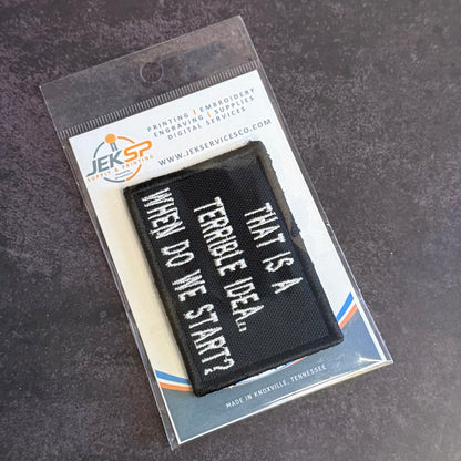 A black rectangular embroidered patch with white text reading 'WHEN DO WE START? THAT'S A TERRIBLE IDEA.
