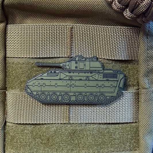 A close-up of a tactical pouch in olive drab canvas with MOLLE webbing, a paracord strap, and an embossed olive drab M2 Bradley tank patch on the front.
