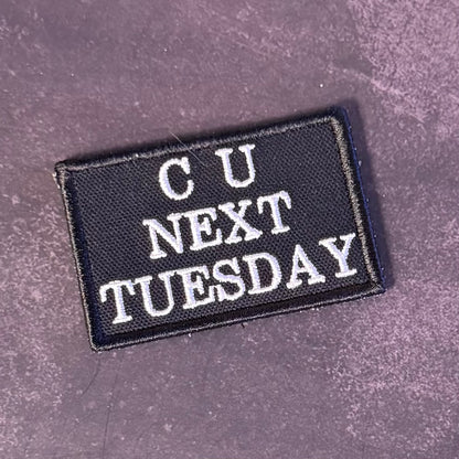A rectangular black embroidered patch with white text reading 'CU NEXT TUESDAY' on a textured dark gray background.