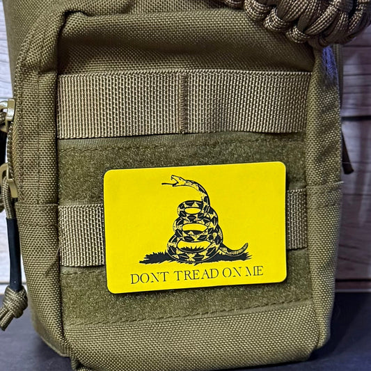 An olive drab tactical pouch with a bright yellow rectangular patch featuring the Gadsden flag design and the text 'DONT TREAD ON ME'.