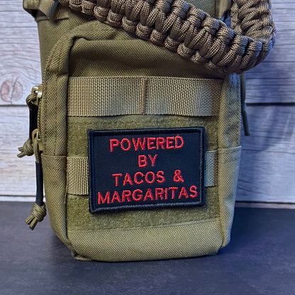 An olive green tactical pouch with a woven strap, featuring a black patch with red embroidered text that reads 'POWERED BY TACOS & MARGARITAS'.