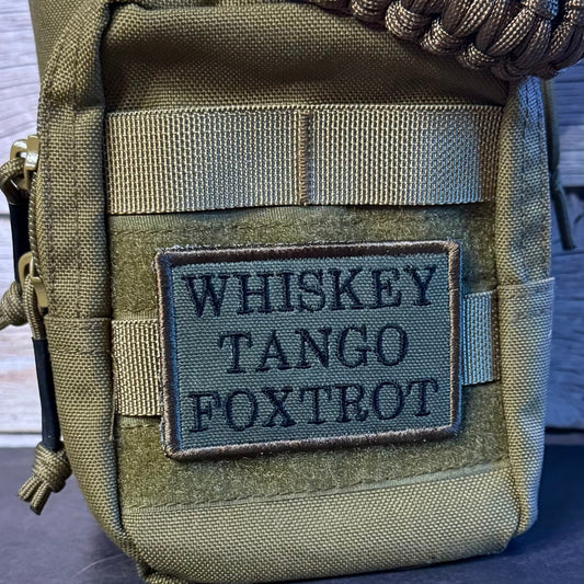 An olive drab tactical pouch with a woven paracord strap, featuring a black embroidered patch that reads 'WHISKEY TANGO FOXTROT'.