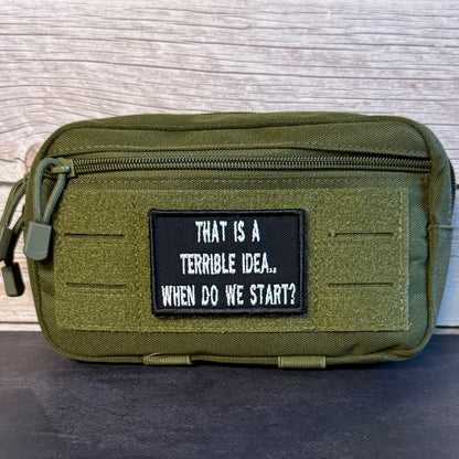 An olive green tactical pouch with a black rectangular patch that reads 'THAT IS A TERRIBLE IDEA.