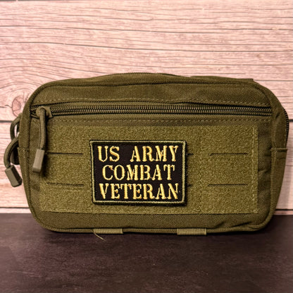 An olive green tactical pouch with a front zipper and a black rectangular patch reading 'US ARMY COMBAT VETERAN' in yellow lettering, shown against a wood plank background.