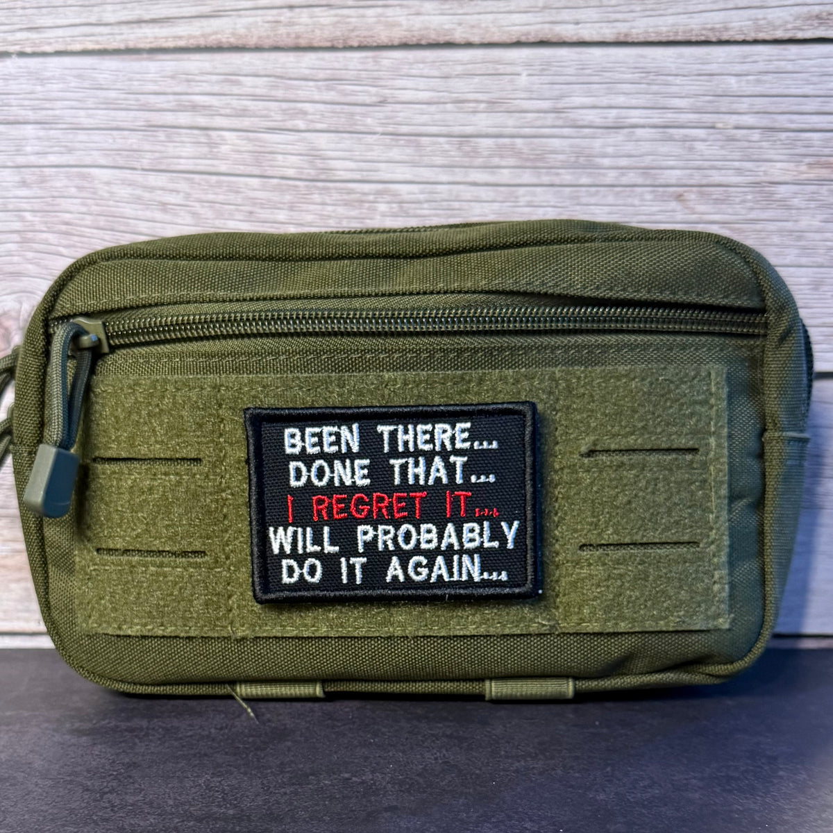 An olive green tactical pouch with a black rectangular patch featuring the humorous quote, 'BEEN THERE.