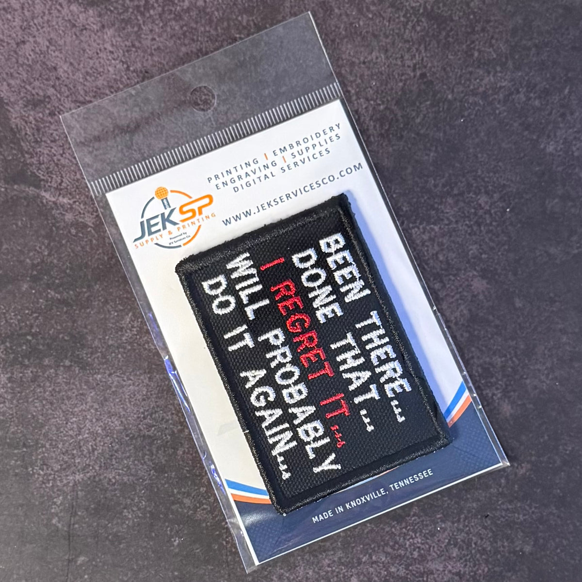 A black rectangular embroidered patch with white and red text reading 'BEEN THERE.